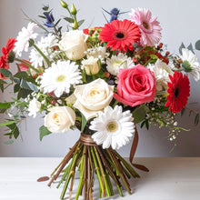 Bouquet of pink and white roses, pink gerbera daisies, and commercial mums with fresh seasonal greenery, arranged in a soft and cheerful style.