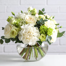 Hand-tied garden-style bouquet in vase  with white Ecuadorian roses, hydrangeas, and seasonal greenery in a soft, natural setting.